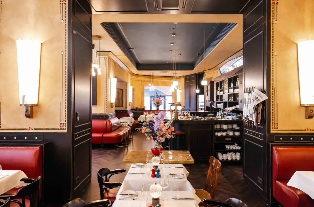 Elegantes Interieur des Restaurants Dorle in Berlin mit roten Ledersitzen, Holzb&ouml;den und einem Blumenstrau&szlig; auf einem Tisch.