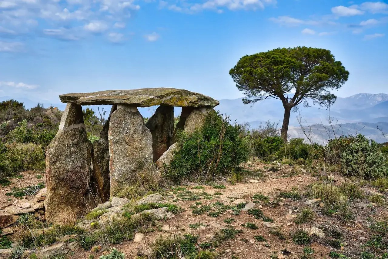 Starożytny menhir, kamienna konstrukcja, stoi na wzgórzu pod błękitnym niebem.