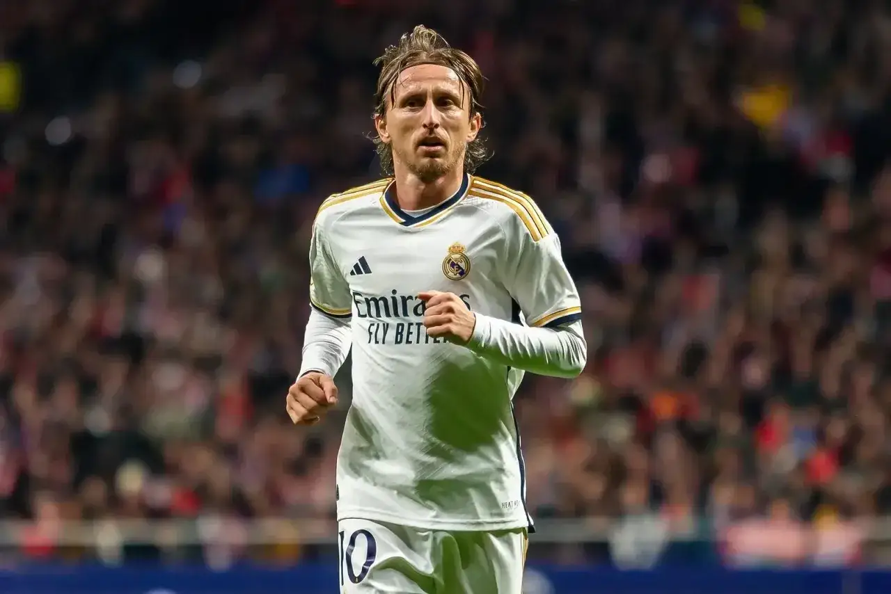 Chorwacki piłkarz Luka Modrić w białej koszulce Realu Madryt, z numerem 10 na spodenkach, biegnie po boisku.