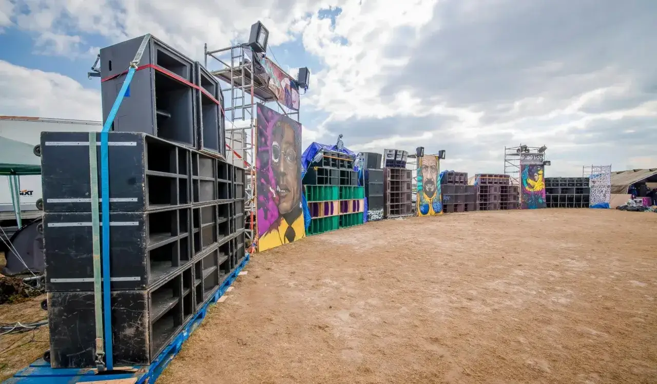 Impianto audio imponente per un festival tekno, con murales colorati che adornano le casse.