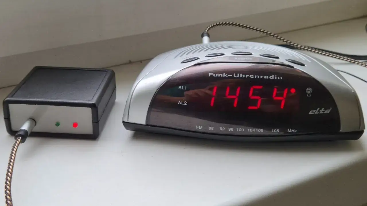 Zegar sterowany radiowo jak działa? Pokazano odbiornik i zegar z czerwonym wyświetlaczem 14:54.