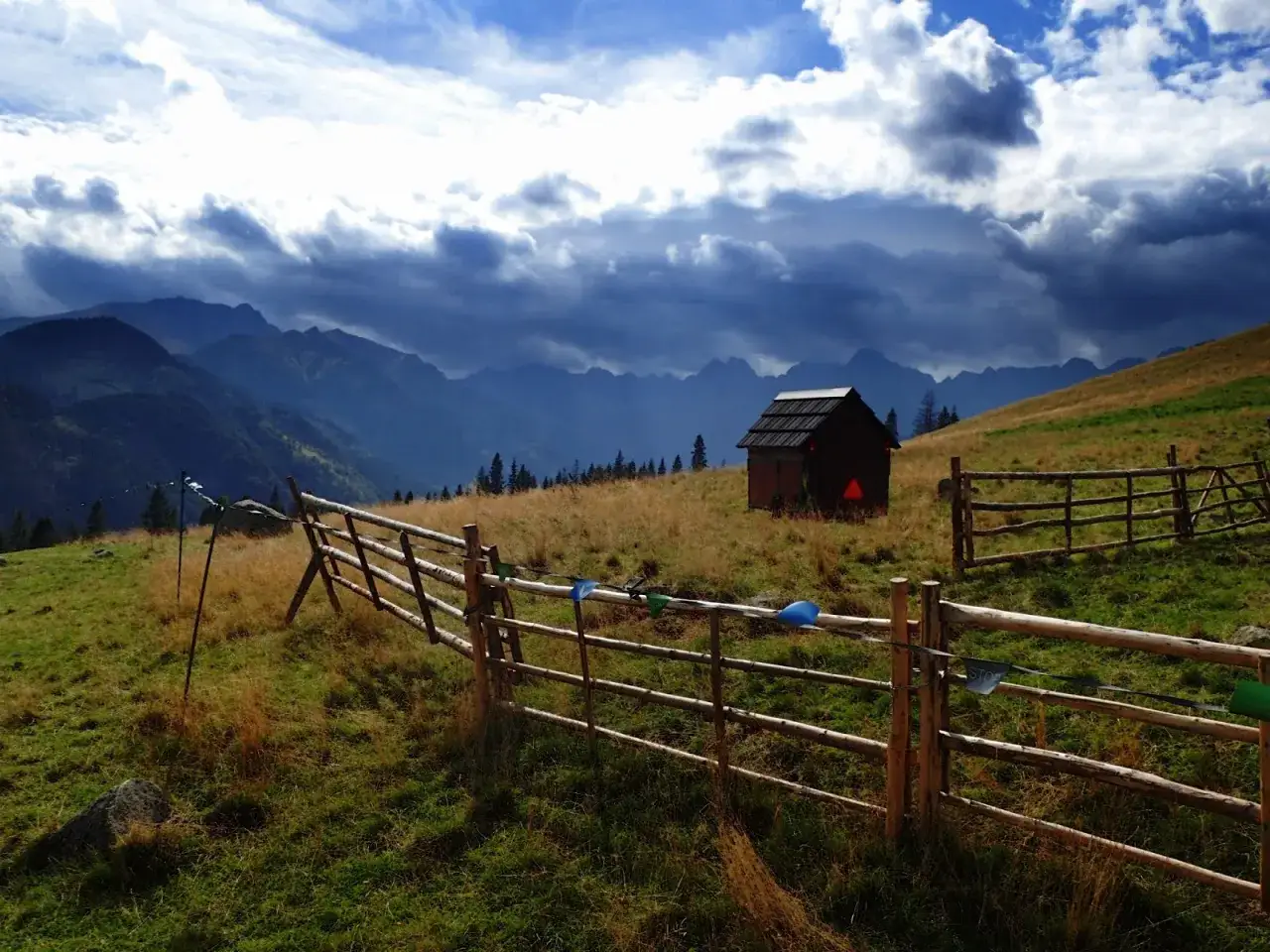 Panorama z Rusinowej Polany. Drewniana szopa i płot na tle górskiego krajobrazu.