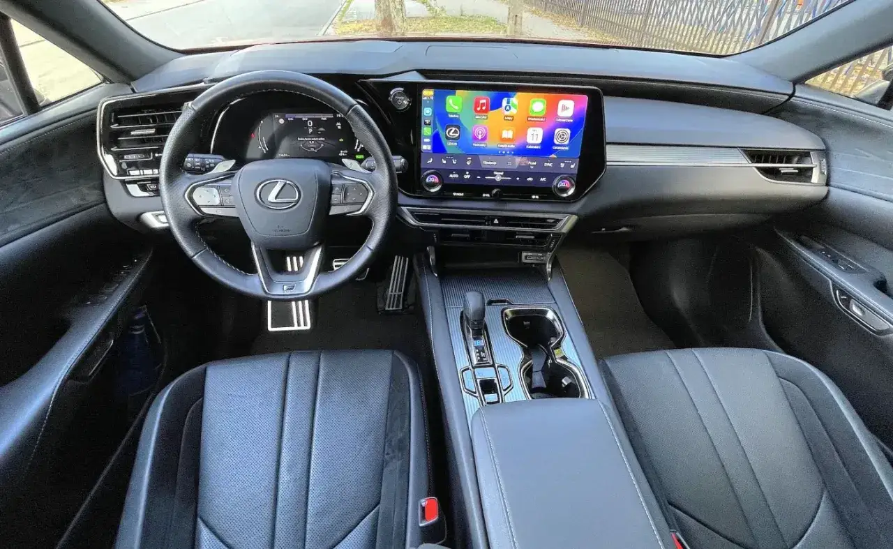 Wnętrze Lexus RX500 z nowoczesnym ekranem multimedialnym, cyfrowymi zegarami i skórzaną tapicerką.