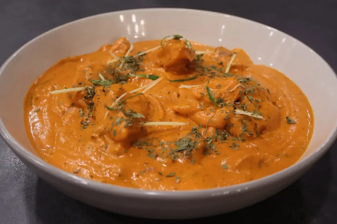 Cremiges Butter Chicken, garniert mit frischen Kräutern und Ingwerstreifen. Ein authentisches Butter Chicken Rezept Original.