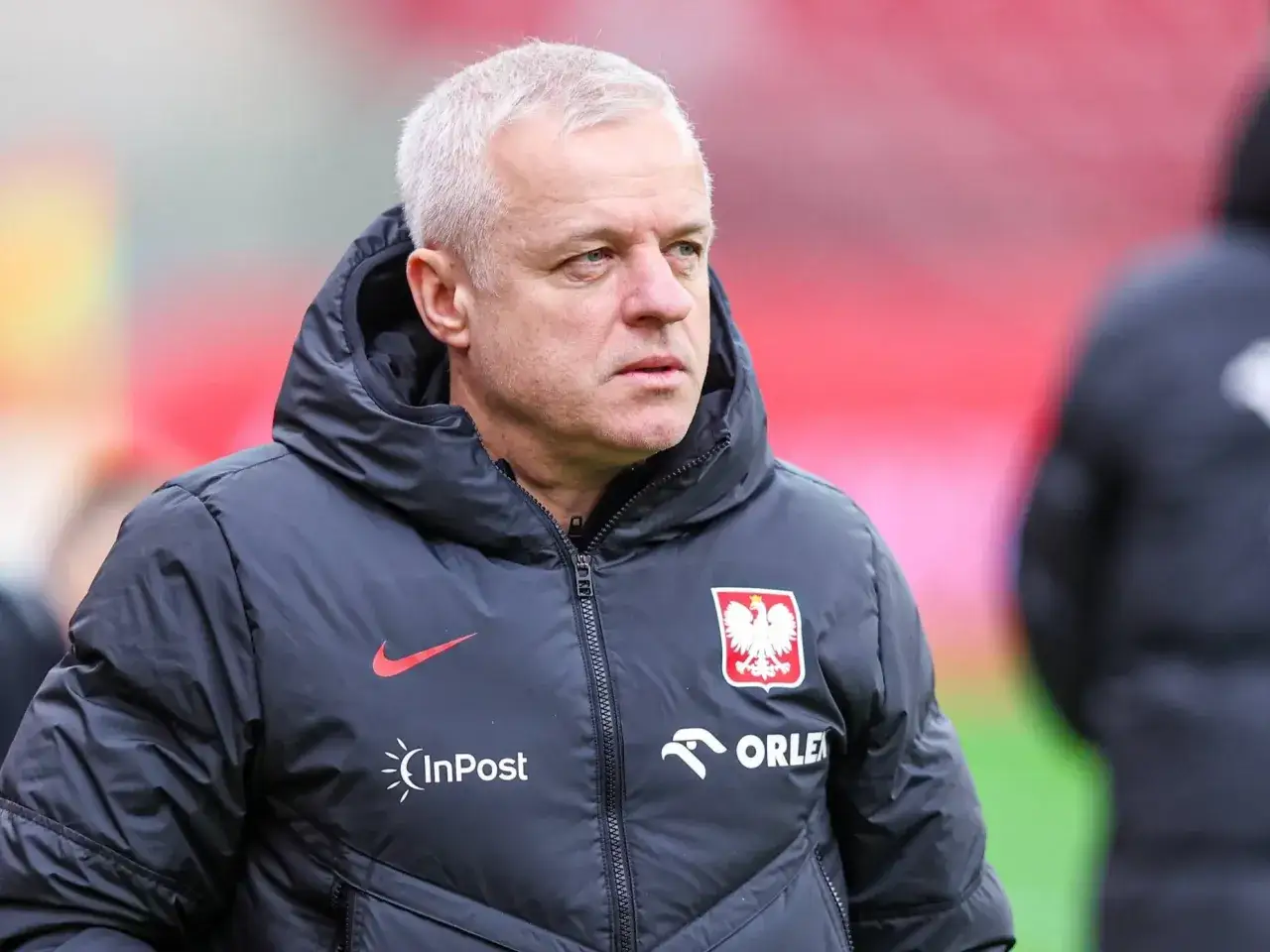 Jacek Jaroszewski, trener reprezentacji Polski, w kurtce z godłem narodowym i logotypami sponsorów.