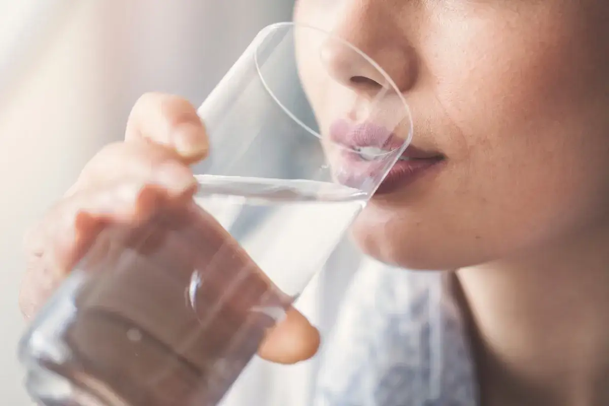 Donna incinta beve acqua per alleviare la bocca secca.