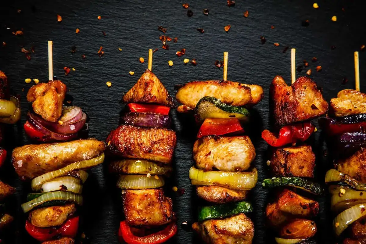 Spiedini di carne succulenti e colorati, alternati a cipolle, peperoni e zucchine, pronti per essere gustati.
