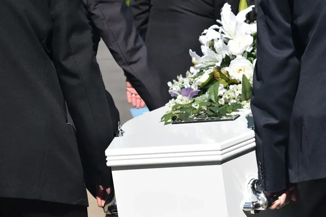 Ostatnia podróż: trumna z kwiatami niesiona do krematorium.