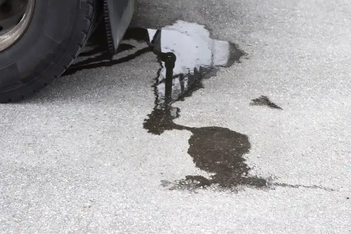 Une flaque sombre sur l'asphalte, pr&egrave;s d'un pneu, indique une fuite liquide de frein.