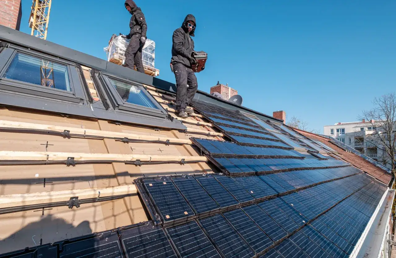 Handwerker installieren Solarmodule auf einem Dach. Die Photovoltaik-Kosten pro m² sind hier ein wichtiger Faktor für die Investition in erneuerbare Energien.