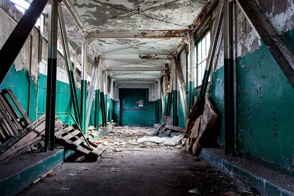 Opuszczony korytarz z zielonymi ścianami i zniszczonymi elementami, idealny do eksploracji, czyli urbex.