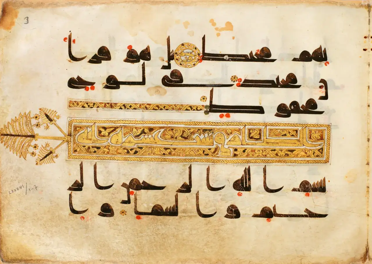 Antiker Koran-Text, der die **Surah Al-Hashr** zeigt, mit kunstvollen goldenen Verzierungen und schwarzer Kalligrafie auf vergilbtem Pergament.