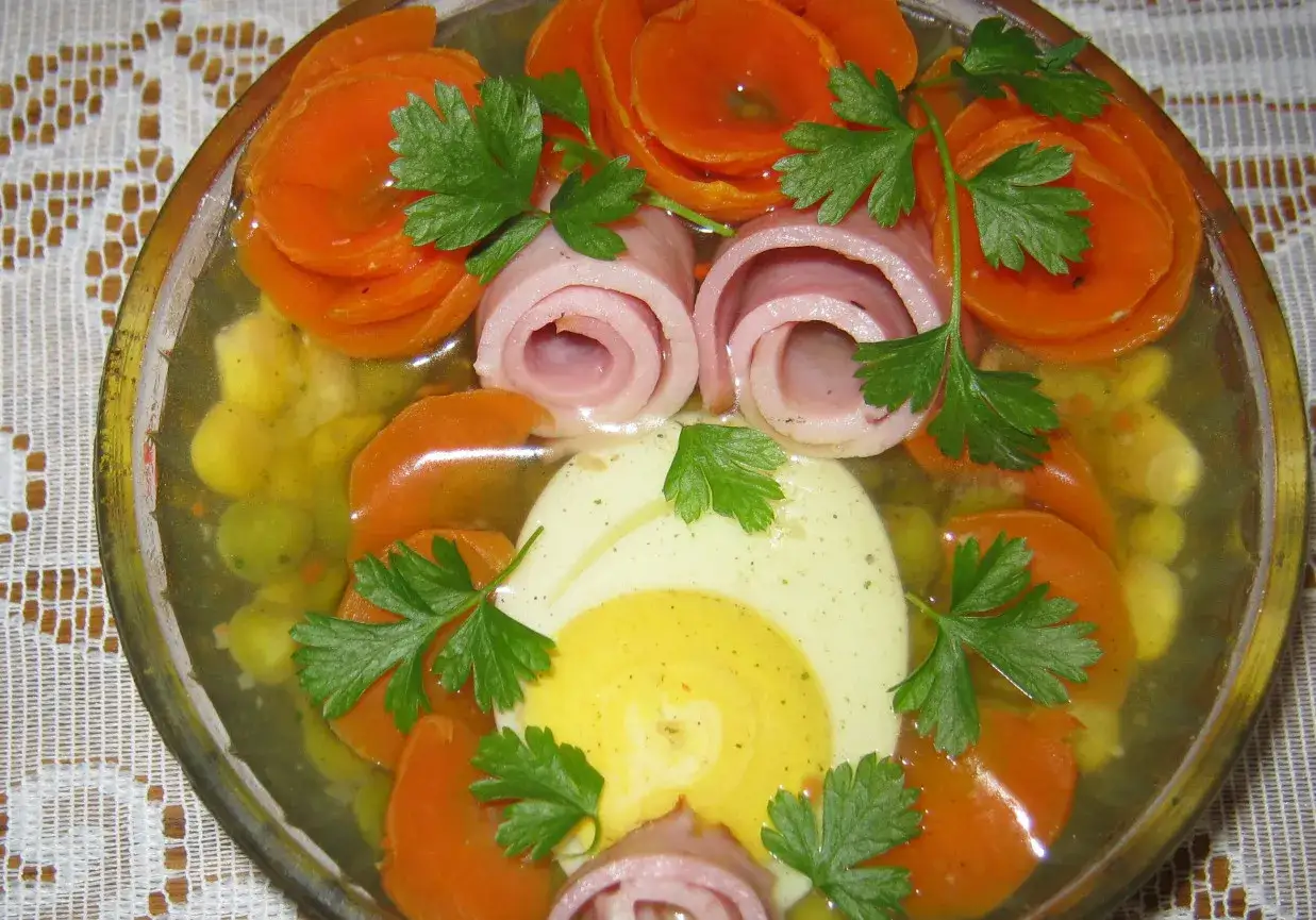 Pyszne jajka w galarecie z marchewką, szynką i groszkiem, ozdobione natką pietruszki. Klasyka polskiej kuchni.