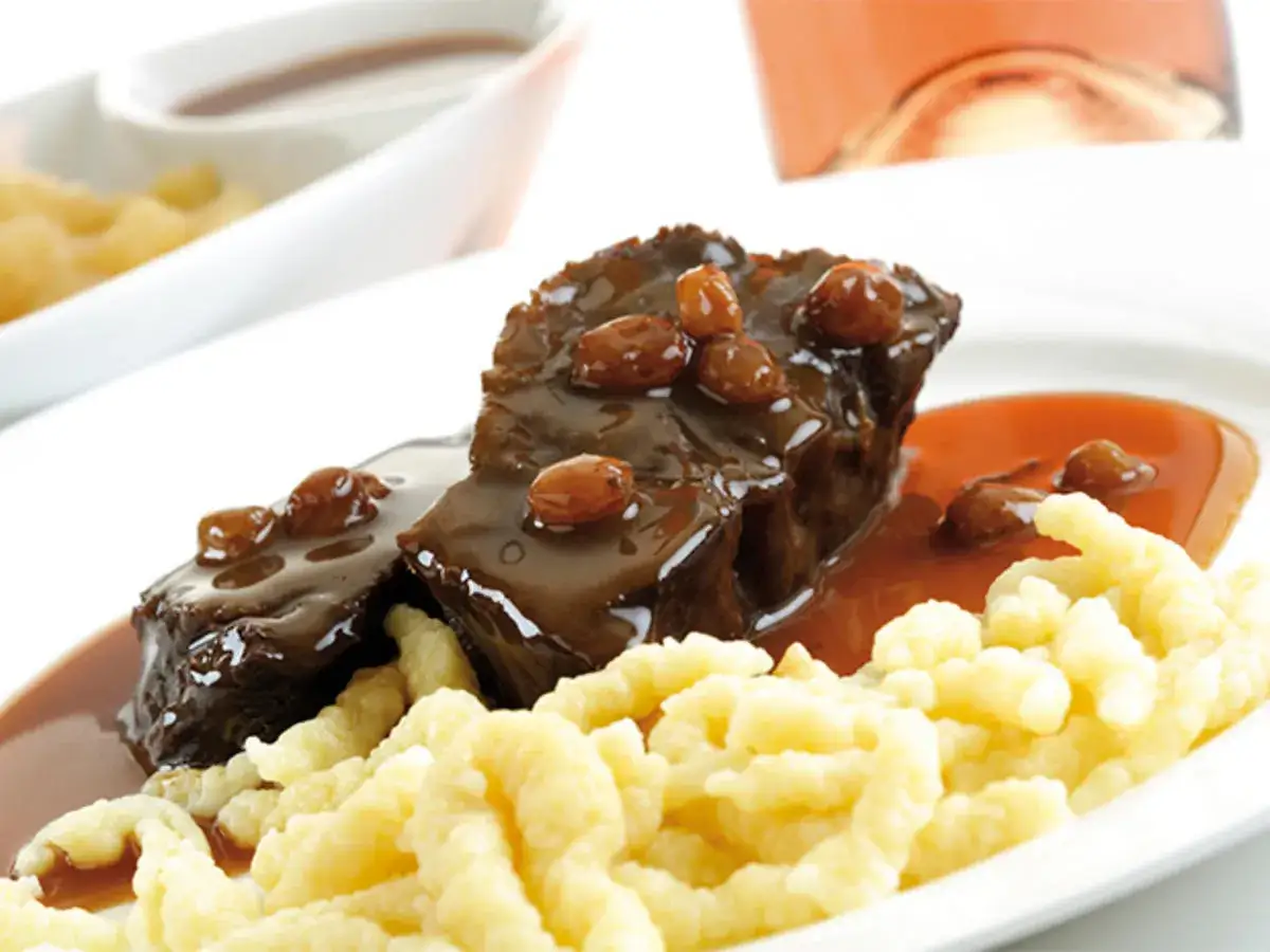 Zwei St&uuml;cke zarter Sauerbraten mit Rosinen in dunkler Sauce, serviert mit Sp&auml;tzle. Ein k&ouml;stliches Sauerbraten Rezept.