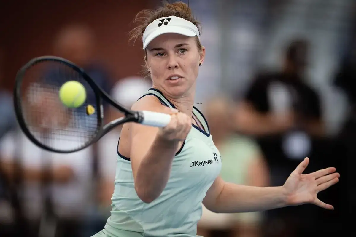 Linda Noskova w akcji, uderza piłkę rakietą. Skupiona na grze, z determinacją na twarzy.