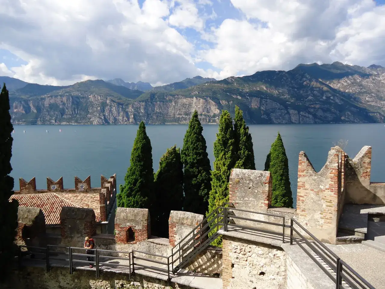 Mura antiche a Desenzano del Garda, con cipressi e il lago sullo sfondo.