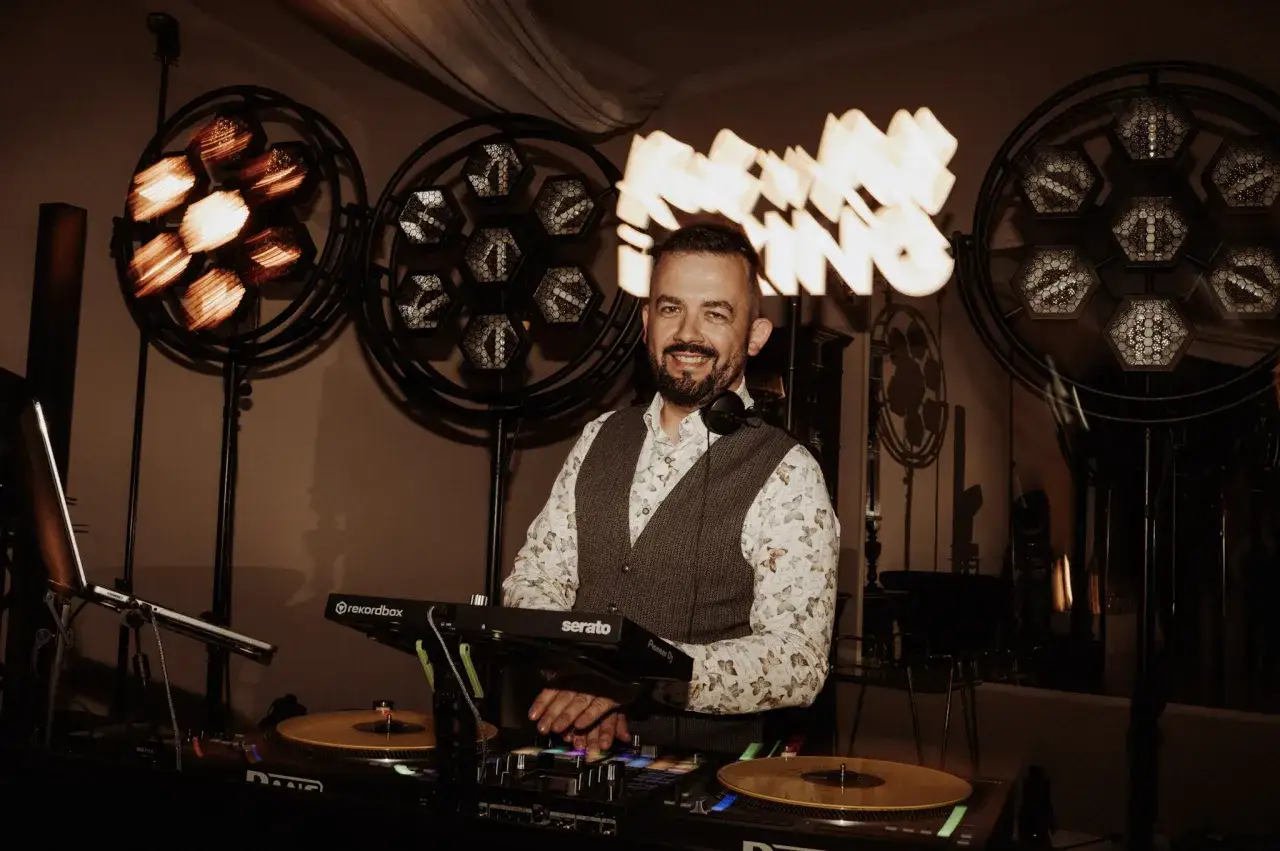 Uśmiechnięty DJ przy konsoli, gotowy do imprezy. Zastanawiasz się, ile kosztuje DJ na wesele?