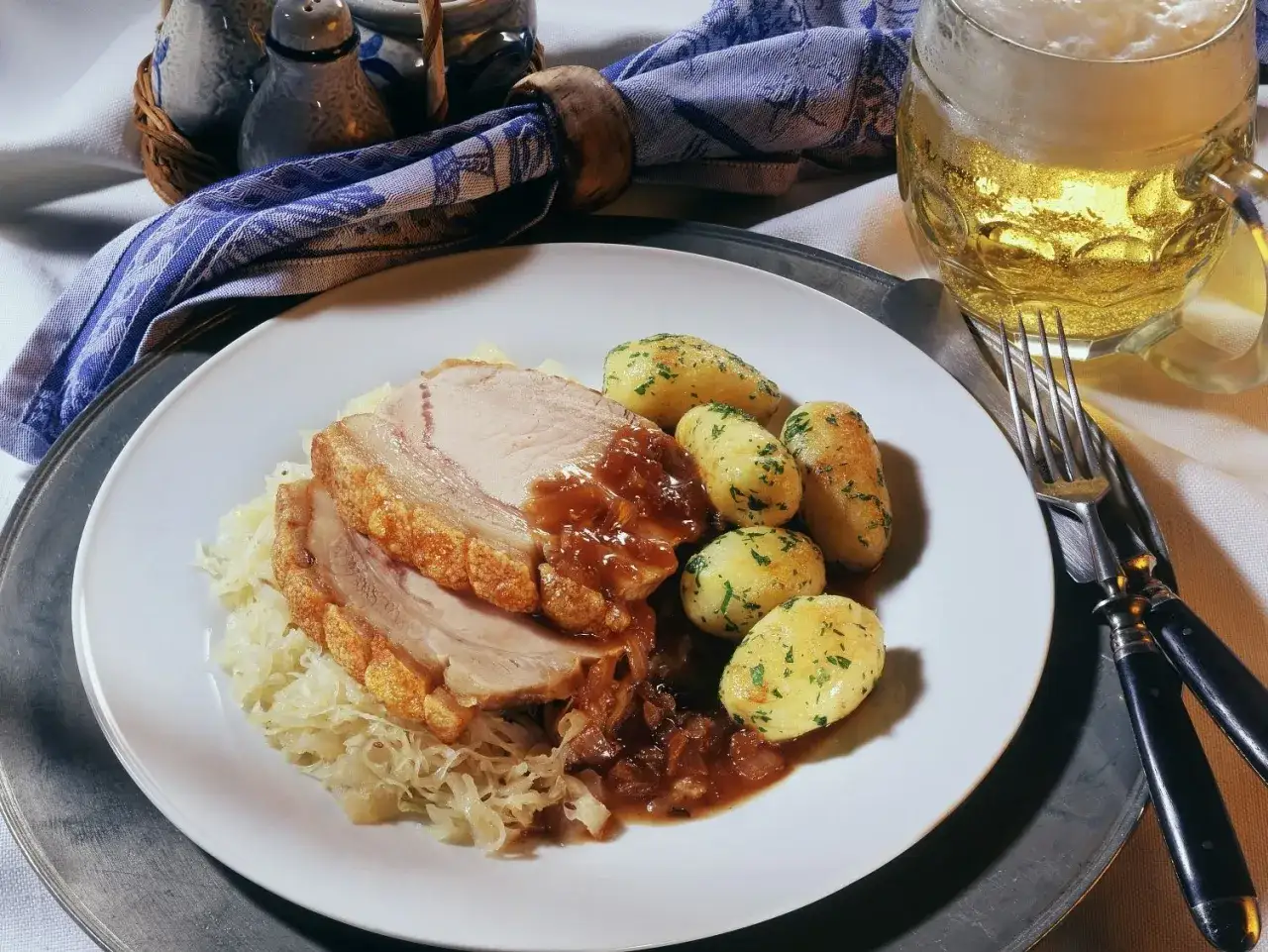 Deftige dicke Rippe mit knuspriger Kruste, Sauerkraut, Kl&ouml;&szlig;en und einem k&uuml;hlen Bier.