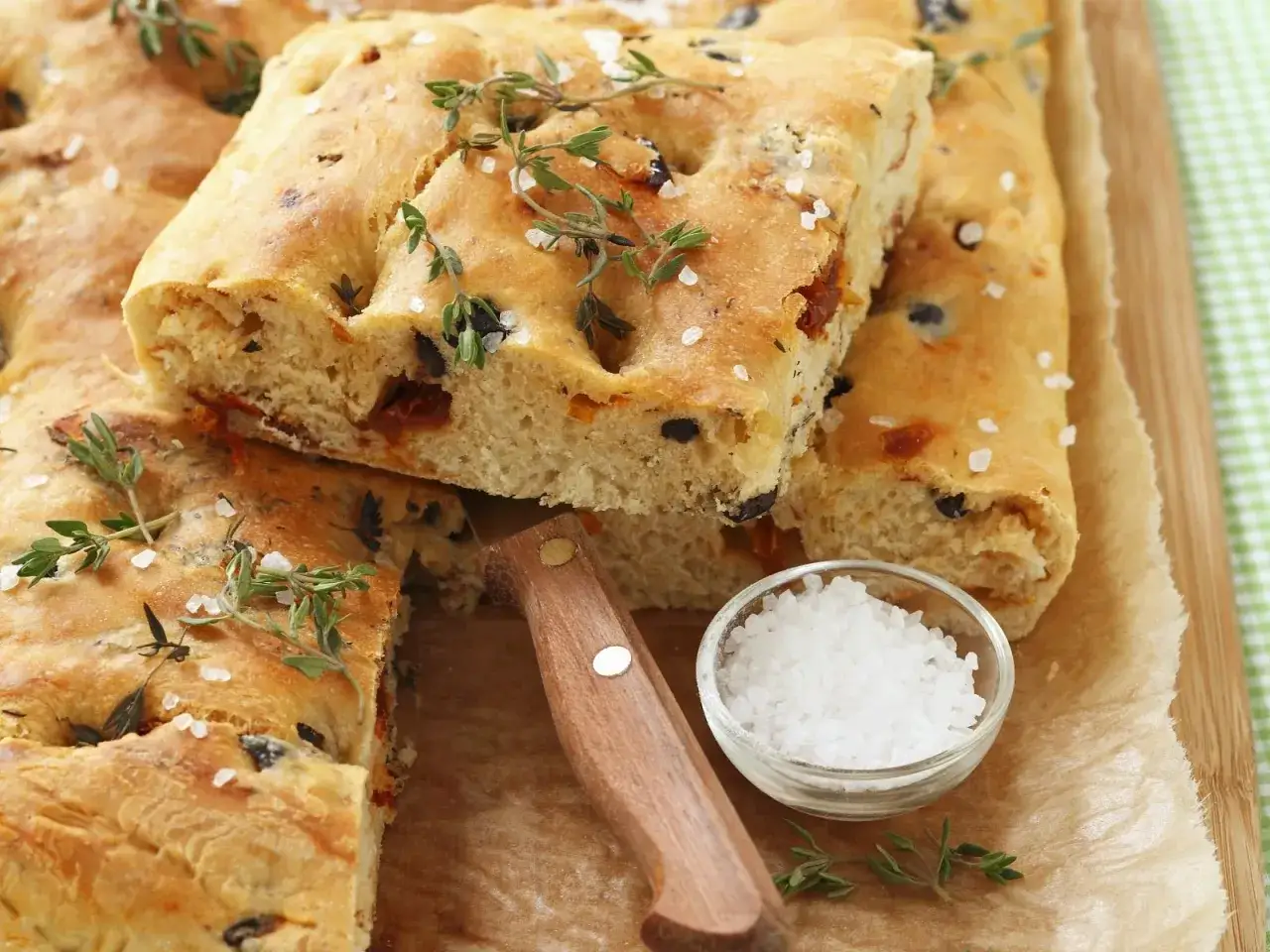 Frisches Focaccia mit Oliven und getrockneten Tomaten, bestreut mit Meersalz und Thymian.