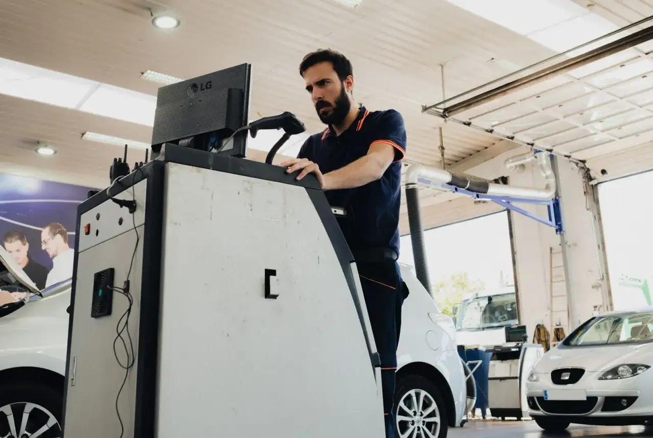 Taller mecánico revisando un coche. El técnico parece preocupado, quizás por un resultado de **itv desfavorable**.