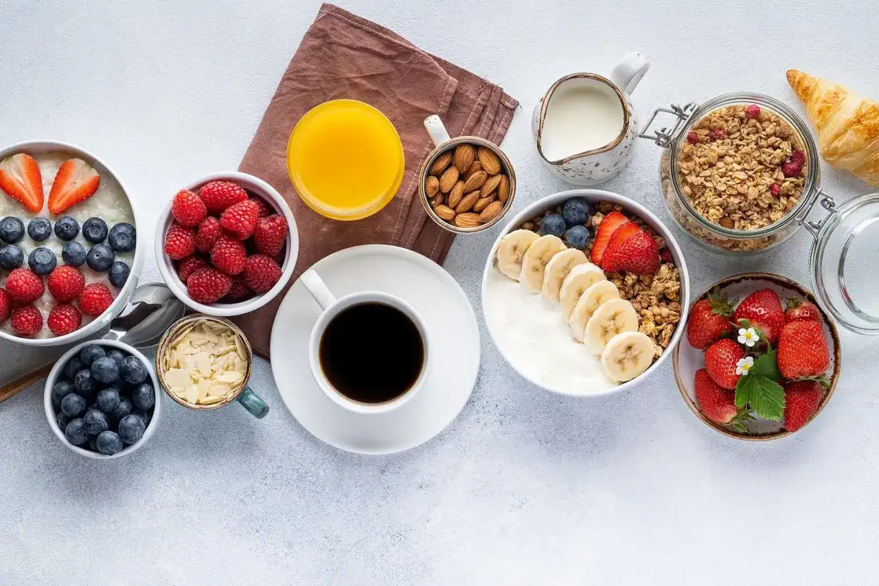 Un pasto sano per iniziare la giornata: yogurt, frutta fresca, muesli, caffè e succo d'arancia. Buone abitudini al mattino per un pieno di energia.