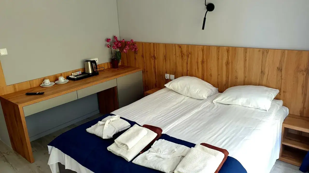 Pokój w sanatorium Sanvit Ciechocinek: dwa łóżka, czajnik, filiżanki i szlafroki czekają na gości.