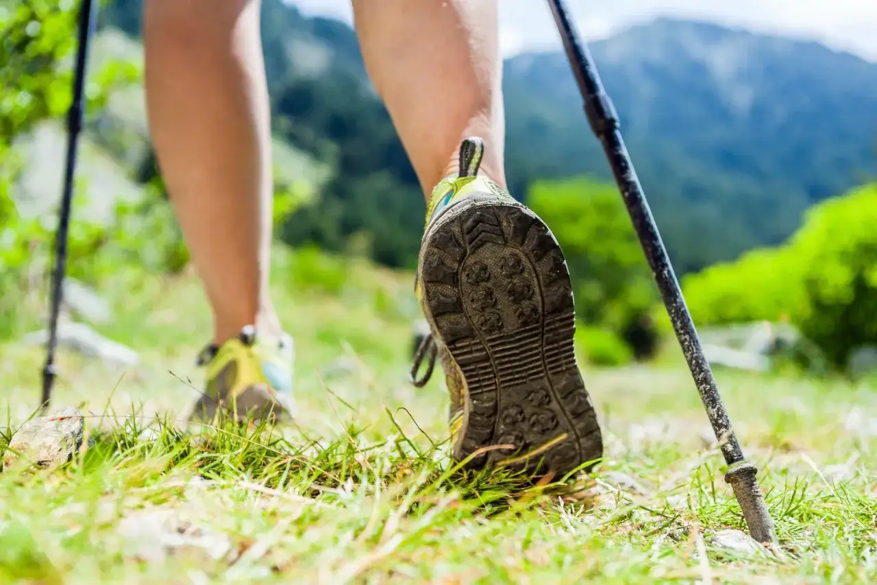 Noga w buciku do nordic walking, gotowa do marszu po g&oacute;rskim szlaku. Poznaj jak prawidłowo założyć buciki na kijki nordic walking.