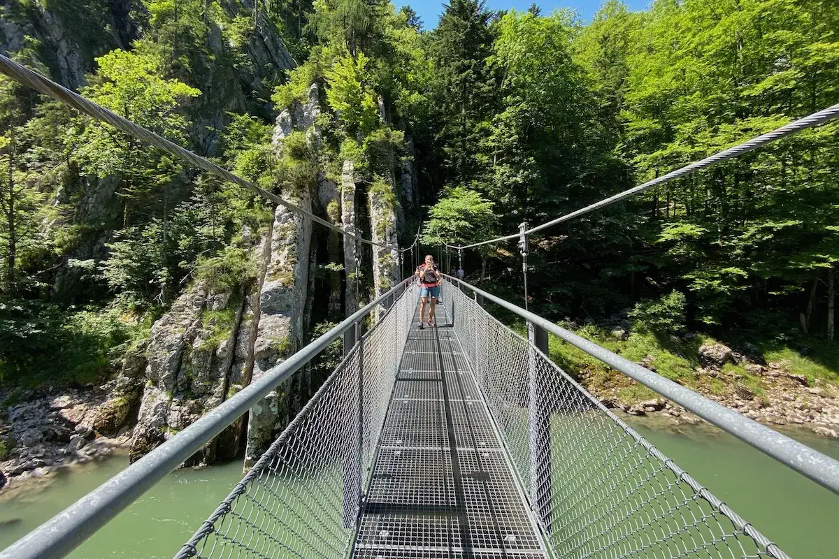 Frau &uuml;berquert H&auml;ngebr&uuml;cke bei der Entenlochklamm Wanderung. Gr&uuml;ne Klamm, Felsen und Fluss.