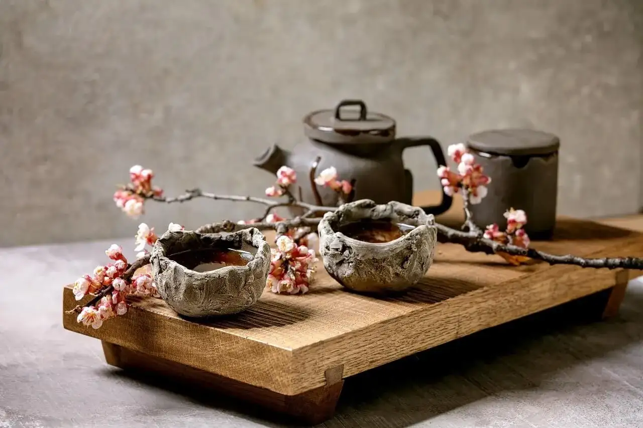 Ceramiczne naczynia i gałązka kwitnącej wiśni tworzą atmosferę wabi sabi wnętrza.