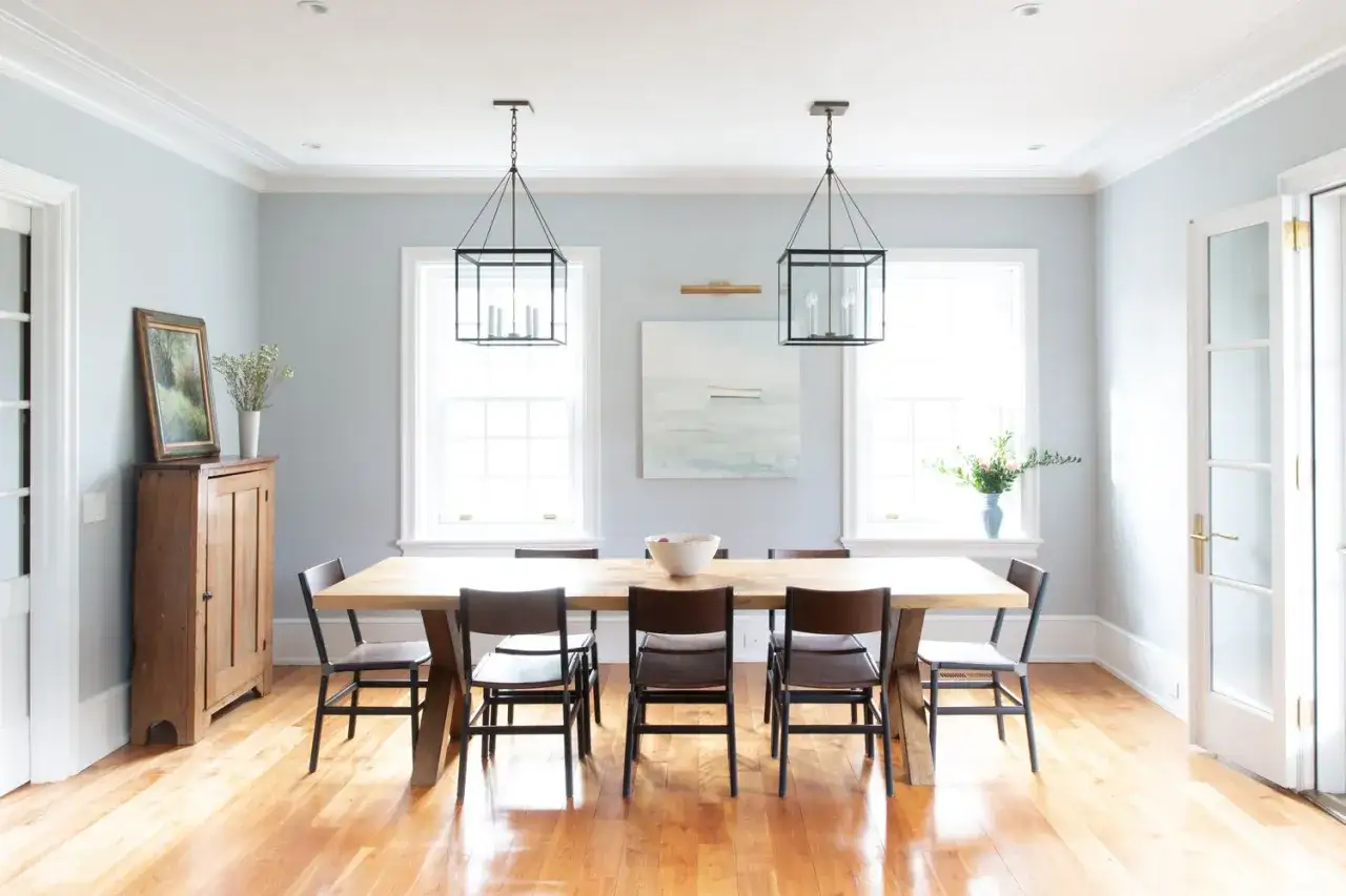 Elegant crown molding ideas enhance this dining room, framing the light blue walls and complementing the modern farmhouse table and chairs.