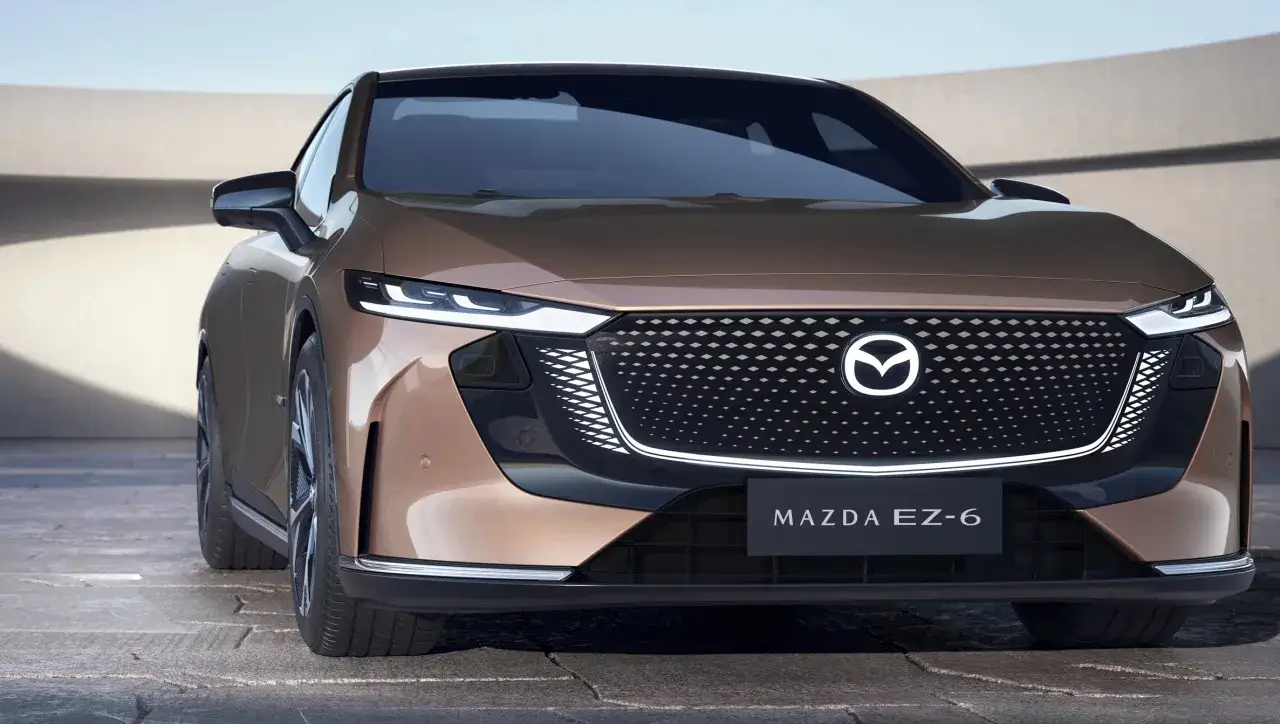 Elegancka, brązowa mazda elektryczna EZ-6 z charakterystycznym grillem i ostrymi światłami LED.