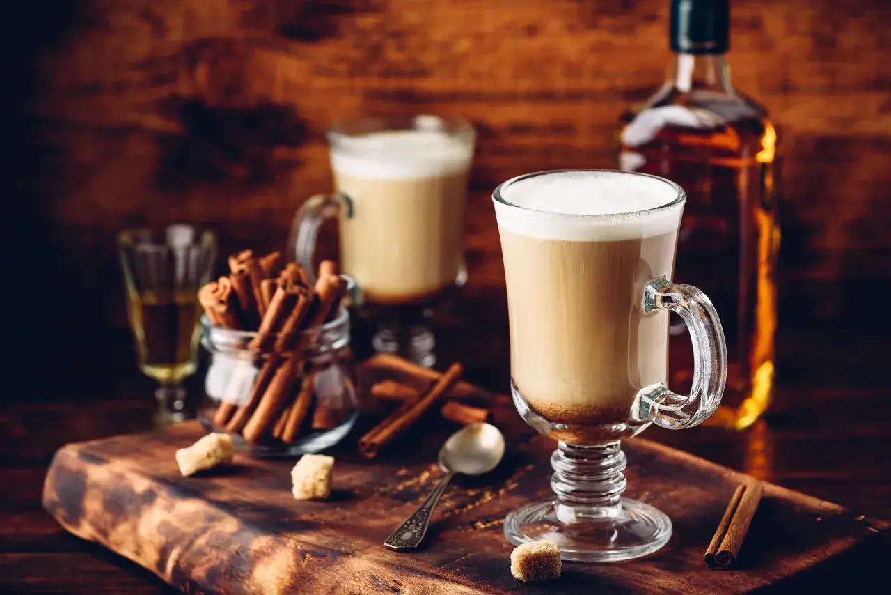 Café chaud avec de la crème, bâtons de cannelle et une bouteille de whisky. Une parfaite recette irish pour se réchauffer.