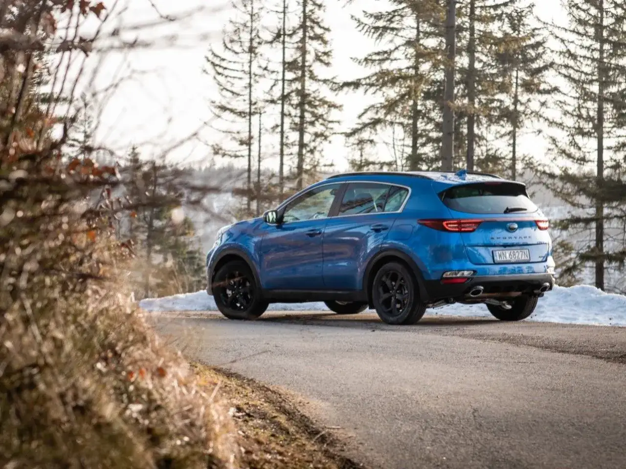 Niebieski Kia Sportage 3 na zimowej drodze. Zastanawiasz się, jakie opony do Kia Sportage 3 będą najlepsze na śnieg i lód?