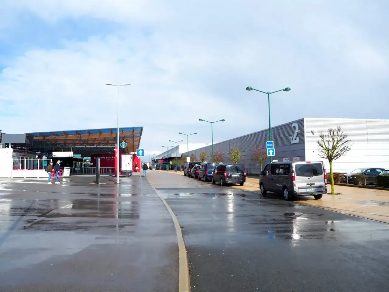 Taxis esperan en el aeropuerto de París Beauvais al centro. El suelo mojado refleja las luces y el cielo nublado.