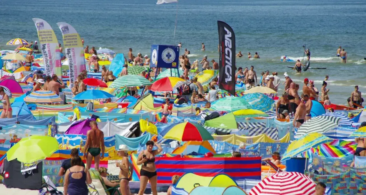 Tłum ludzi na plaży, kolorowe parawany i parasole. Szukasz miejsca, gdzie najtaniej nad morzem? Tu jest mnóstwo słońca i zabawy!