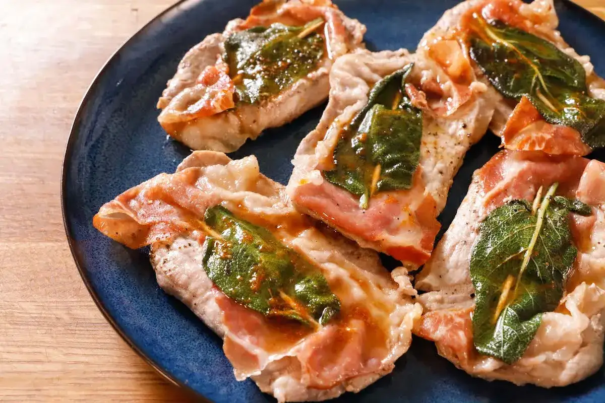 Saltimbocca alla romana ricetta originale: fettine di vitello con prosciutto e salvia, cotte in padella con il loro sughetto.