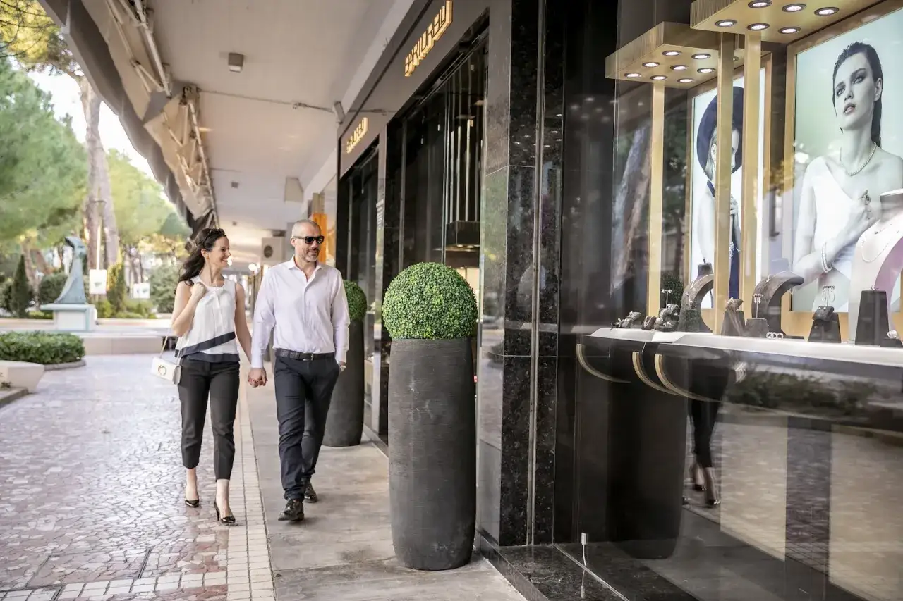Coppia passeggia mano nella mano nel centro di Milano Marittima, ammirando le vetrine di lusso.