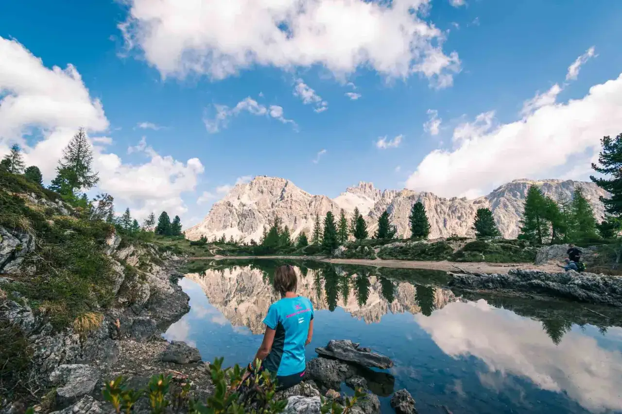 Donna ammira il riflesso delle montagne nel **lago di Limedes**.