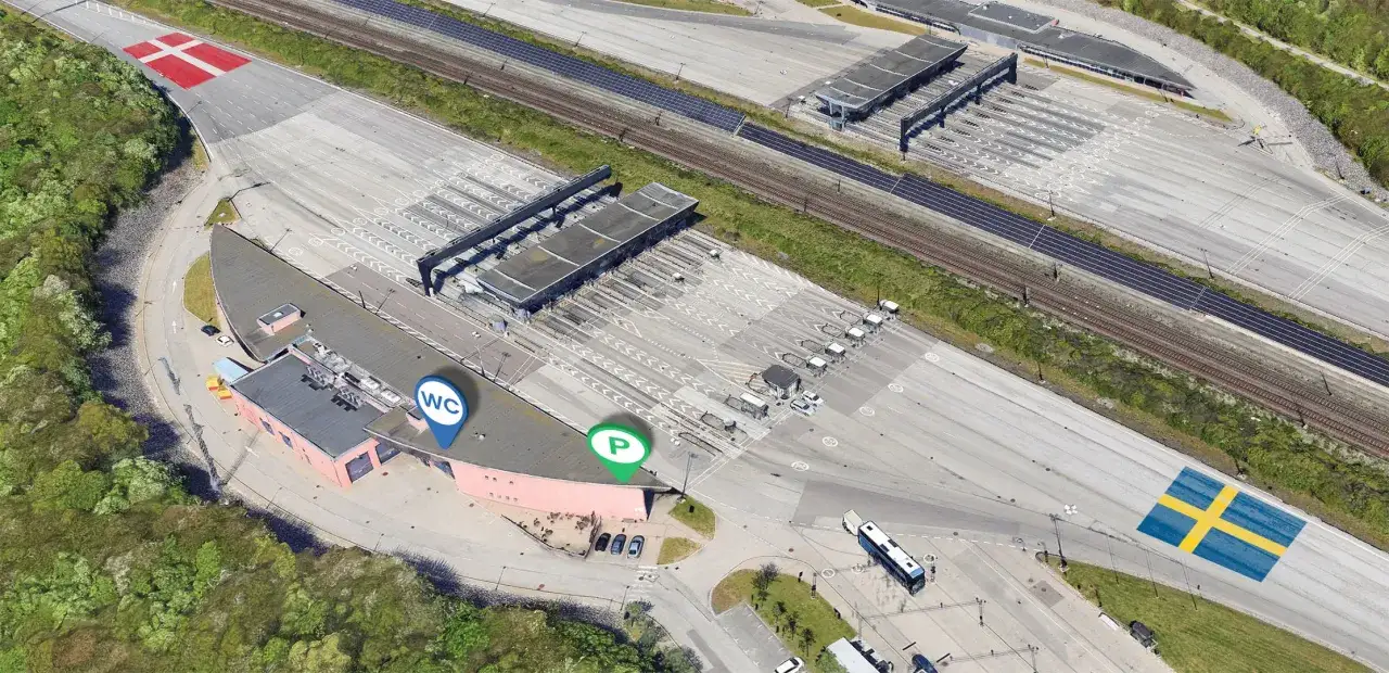 Płatny most Oresund. Gdzie kupić bilet? Znaki wskazują parking i toalety. Flagi Danii i Szwecji.