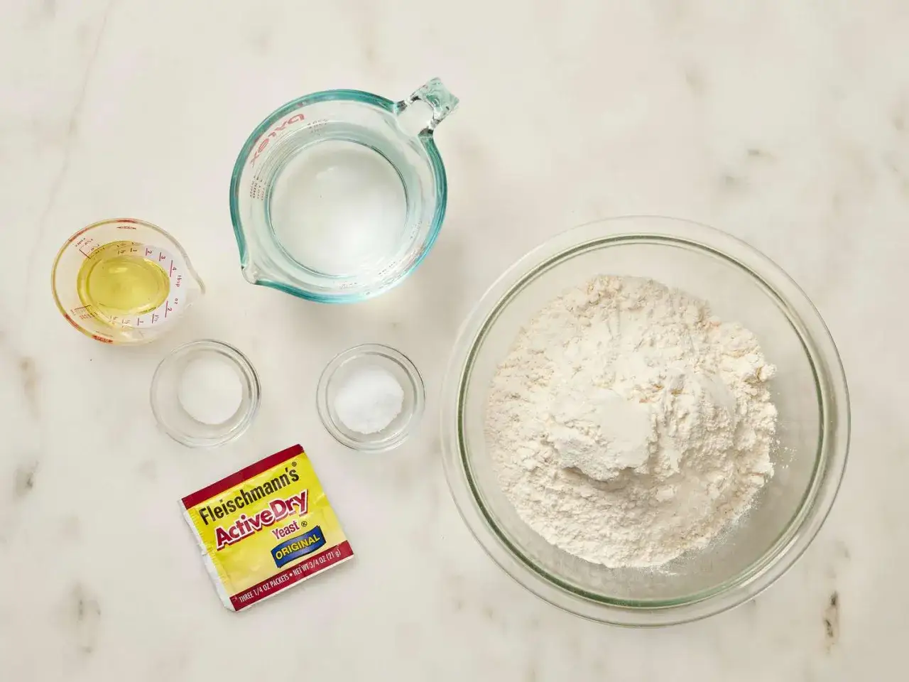Ingrédients pour une recette pâte à pizza rapide : farine, eau, levure, sel et huile.
