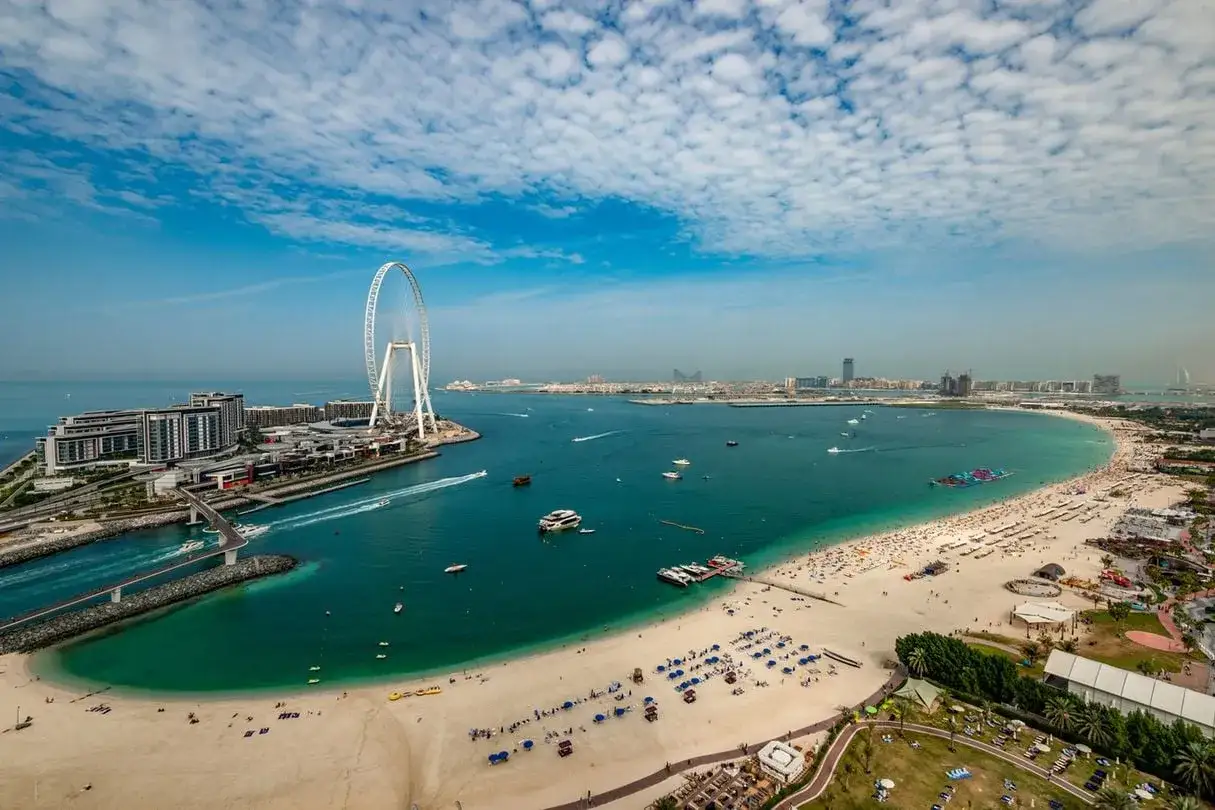 Wspaniały widok na Dubaj z dzieckiem: plaża, morze, diabelski młyn i nowoczesne budynki. Idealne miejsce na rodzinne wakacje.