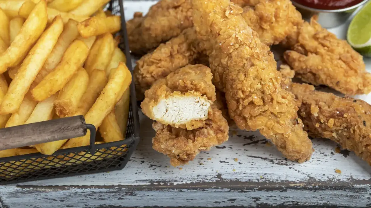 Straccetti di pollo impanati croccanti e patatine fritte dorate, un classico per un pasto gustoso.