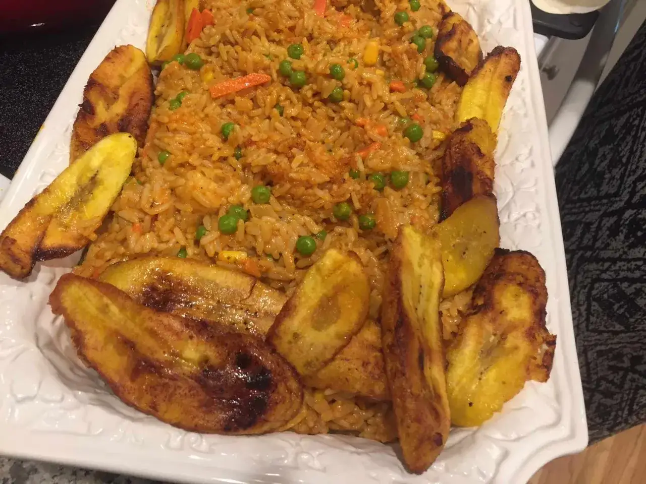 Ein Teller mit Jollof Rice, garniert mit gebratenen Kochbananen. Ein Festmahl, das die Aromen Afrikas vereint.
