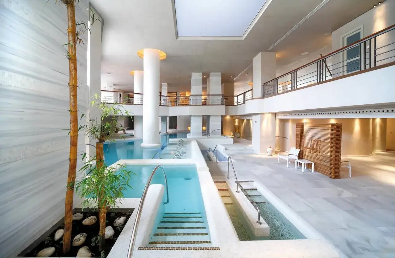 Piscinas y cascadas de agua en el spa del Royal Hideaway Sancti Petri, con bambú y mármol.