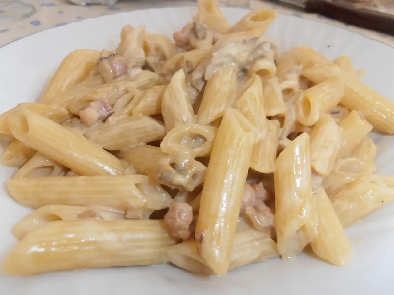 Penne cremose con funghi e pancetta, un piatto di pasta alla boscaiola che invita a gustare i sapori del bosco.