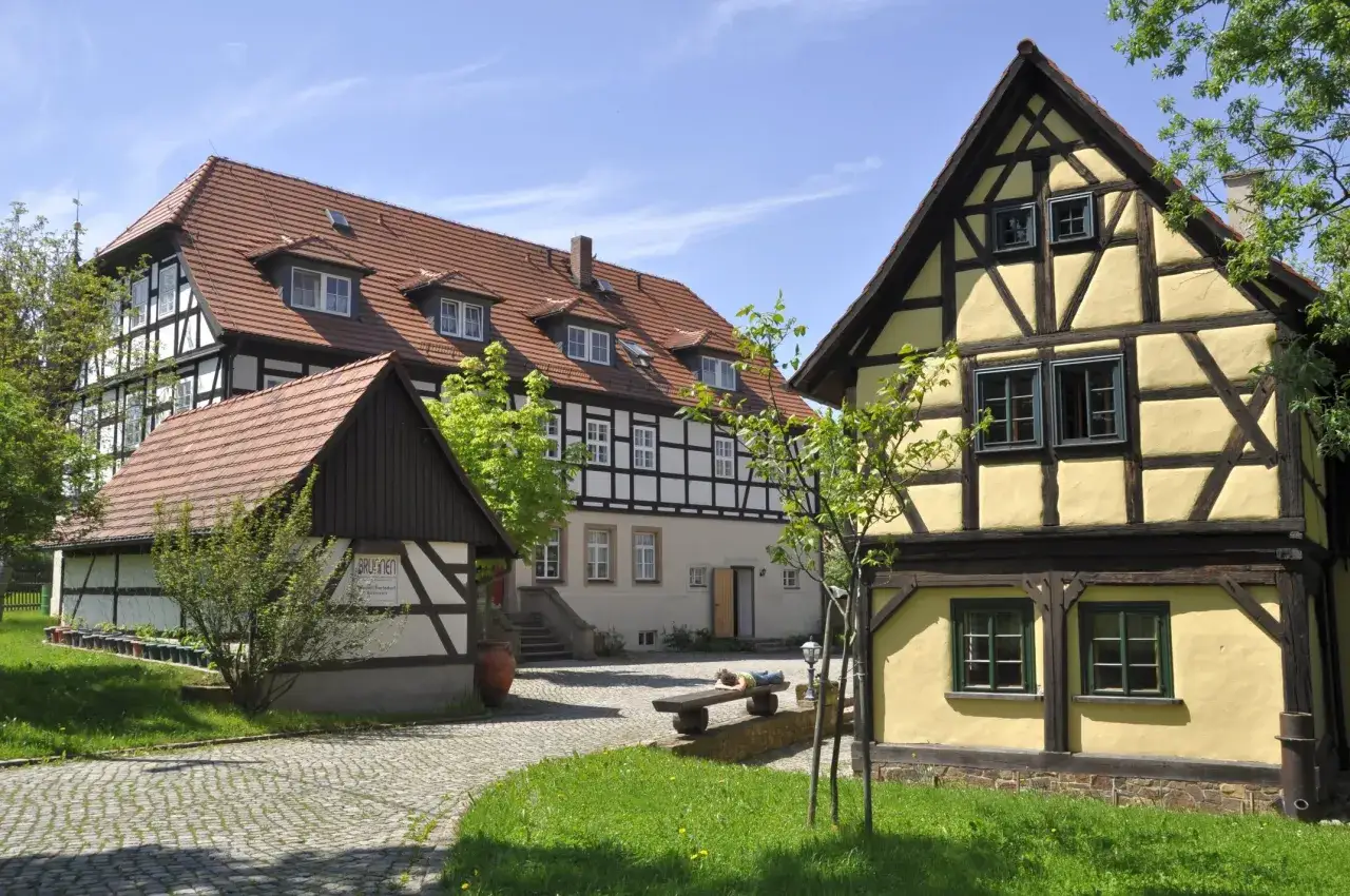 Fachwerkhäuser mit roten Ziegeldächern. Ein Mann ruht auf einer Bank im Hof. Perfekt für ein Wochenende mit Gott.