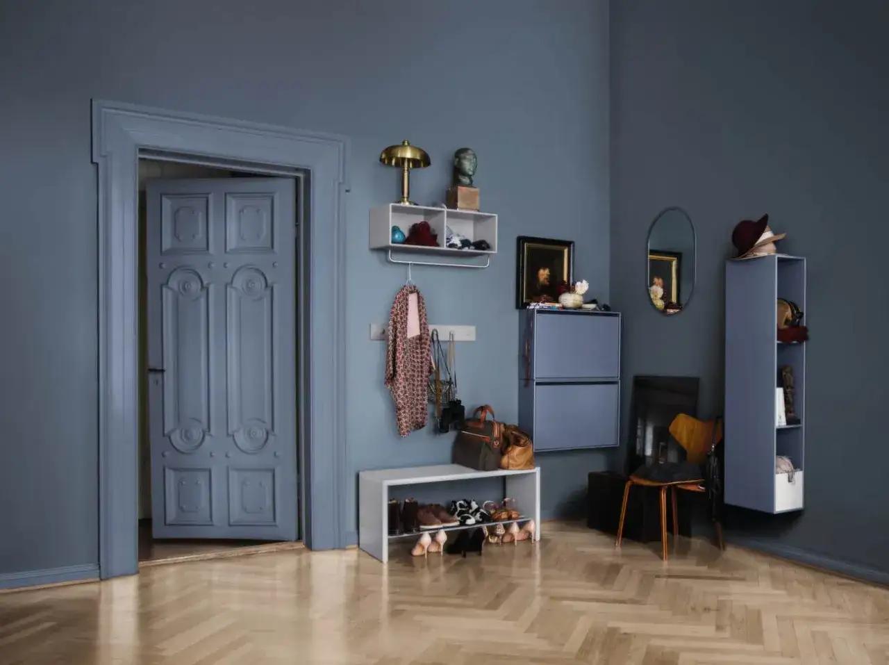 Grå hall inspiration med en öppen dörr, skohylla, vägghängd förvaring och en spegel.