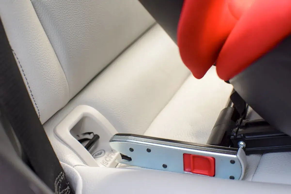 Jak zamontować fotelik w samochodzie instrukcja: zaczep ISOFIX wpięty w uchwyt fotelika na jasnej, sk&oacute;rzanej kanapie.