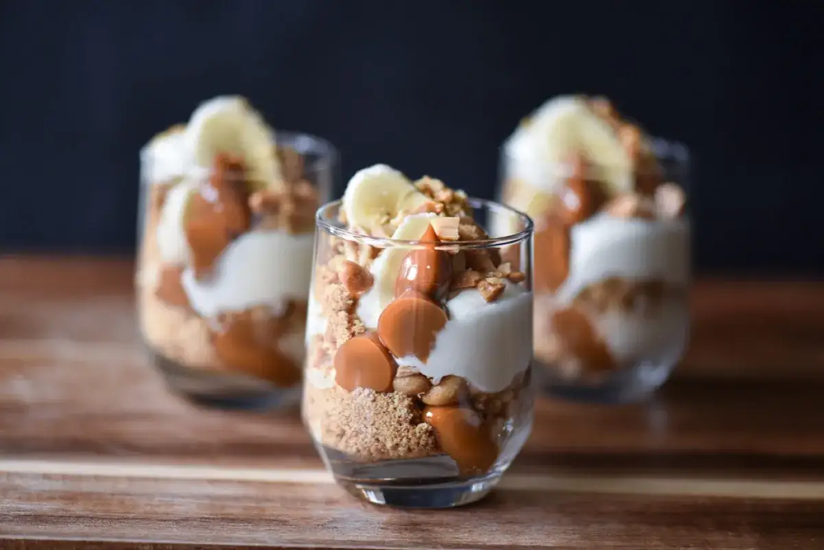 Tre läckra banoffee paj i glas med banan, kolasås och kexsmulor.