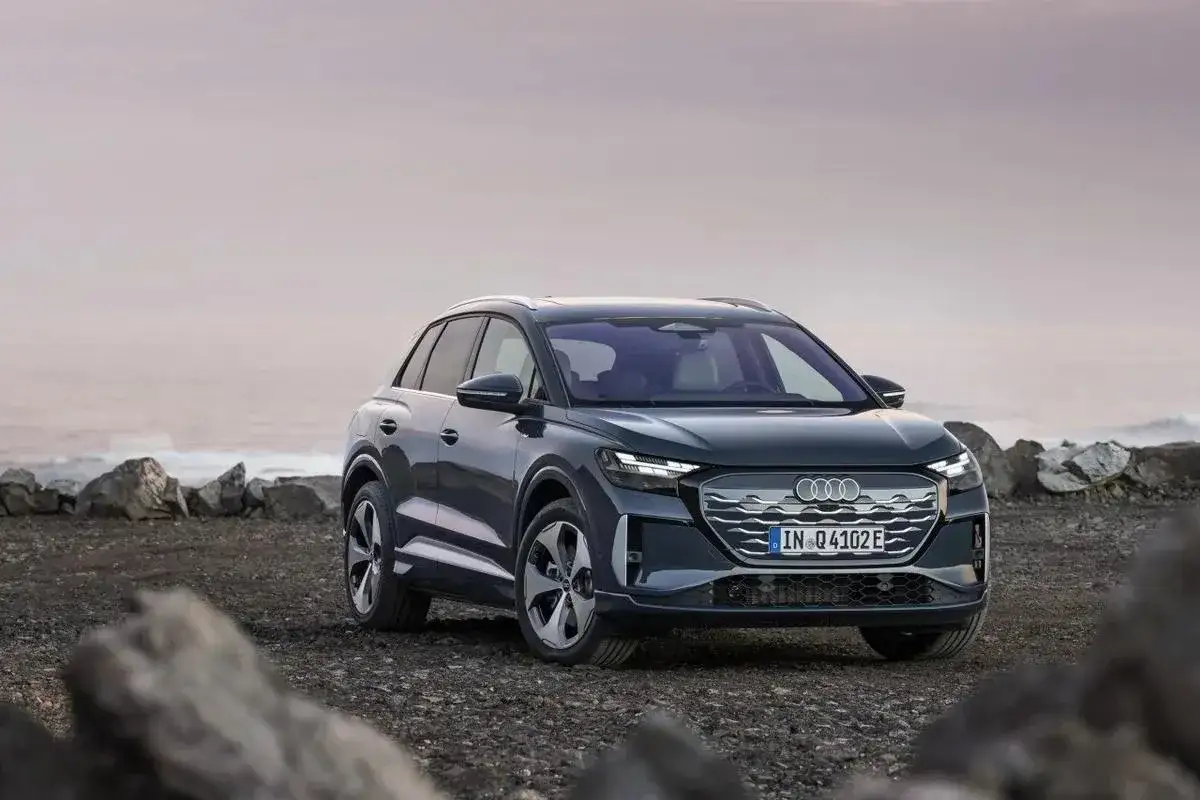 Ciemnoszary Audi Q4 stoi na kamienistej plaży.